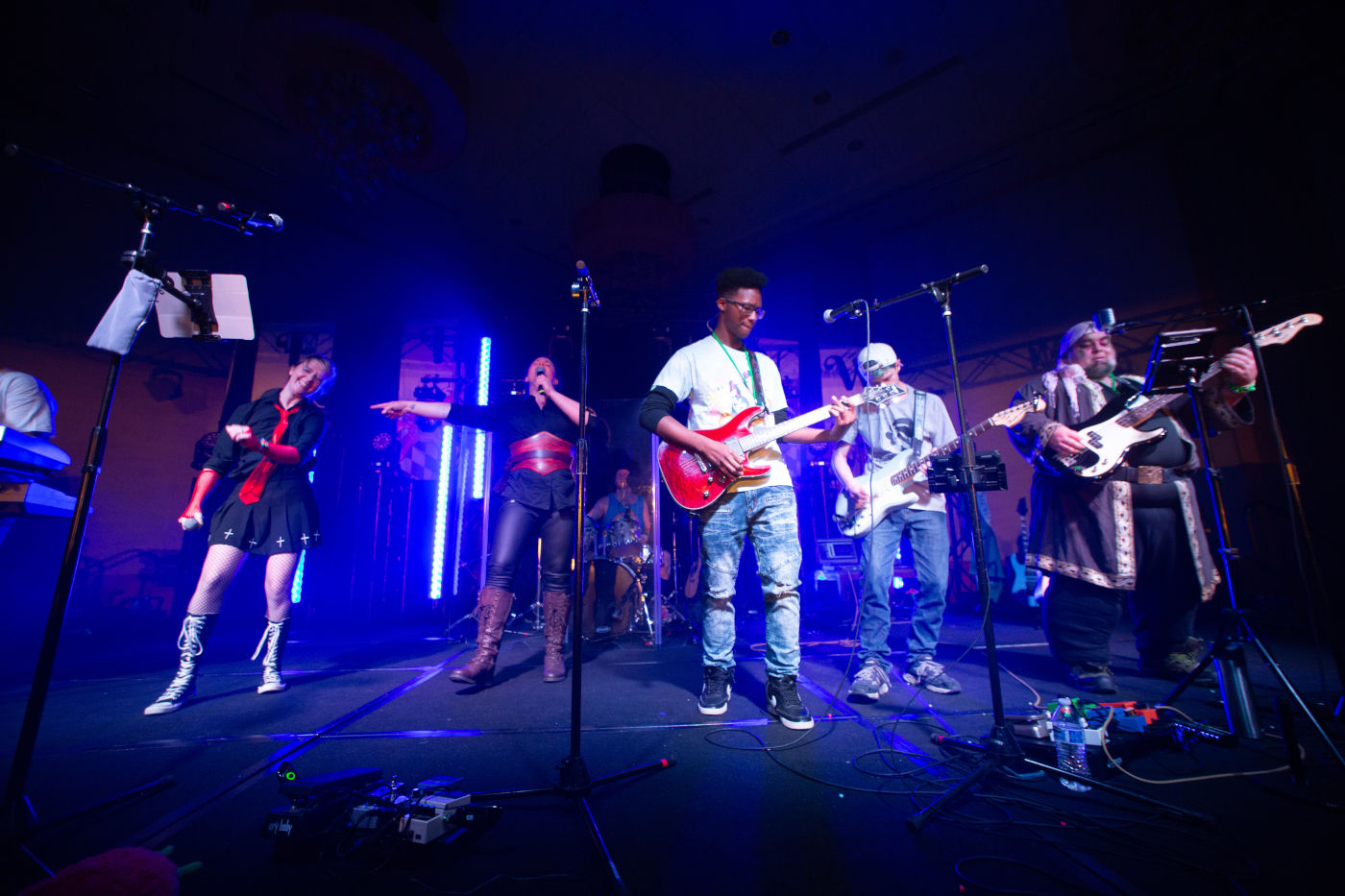 Musicians singing and playing electric guitar on stage.