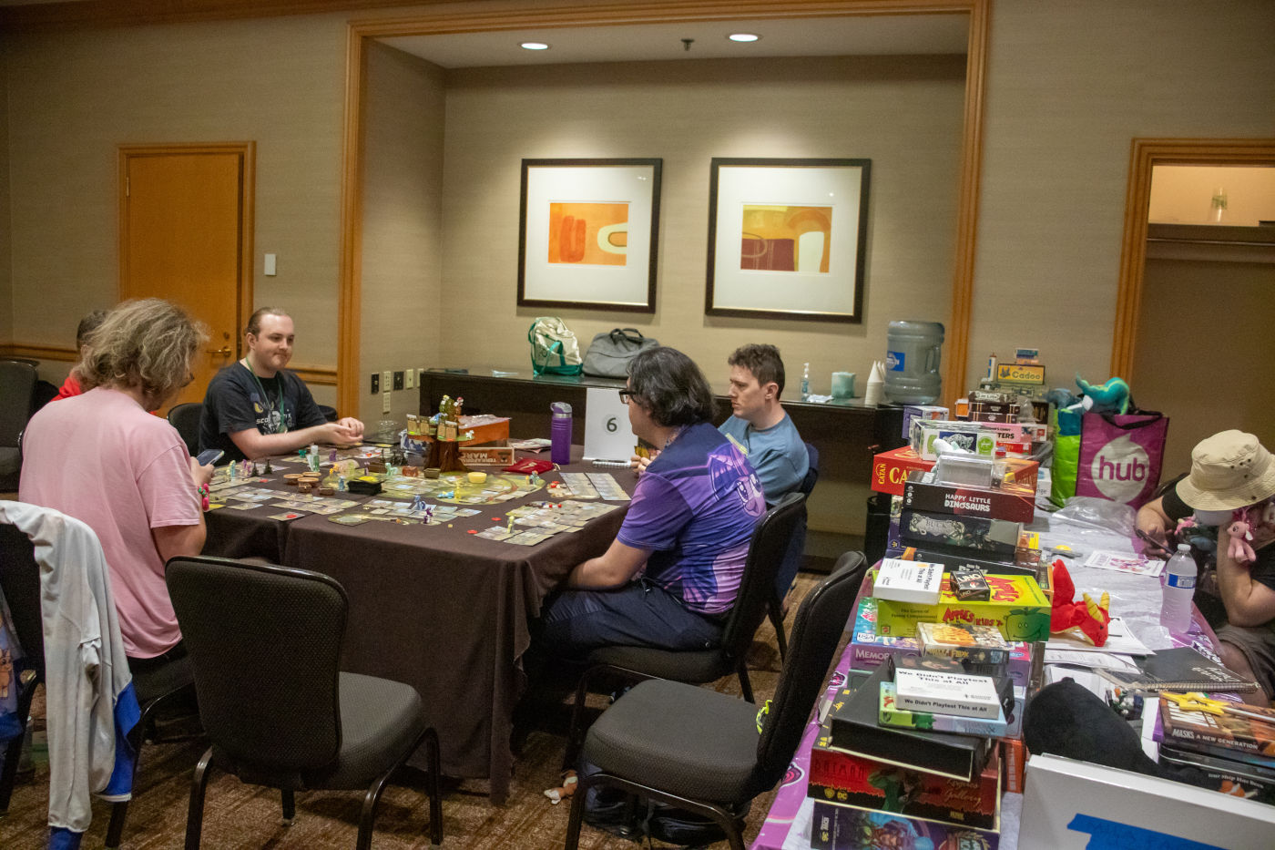 A group of attendees playing a tabletop game, with other game boxes on another table.